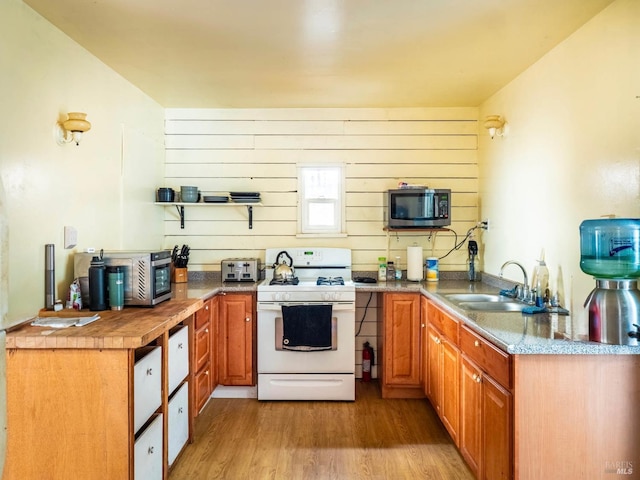 5820 Ruddock Rd N, Philo, CA 95466 - kitchen featuring white gas stove, stainless steel microwave, light wood finished floors, brown cabinets, and wood walls