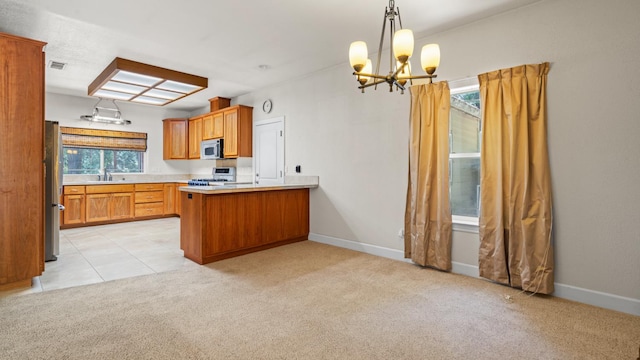 2077 Bourbon St, Pollock Pines, CA 95726 - kitchen featuring appliances with stainless steel finishes, a chandelier, a peninsula, light carpet, and brown cabinetry