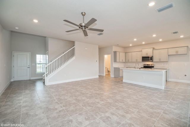 kitchen featuring ceiling fan, light tile patterned floors, sink, a kitchen island with sink, and appliances with stainless steel finishes