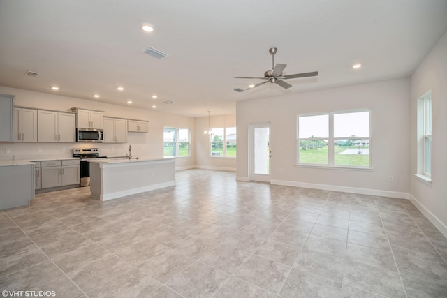 kitchen with gray cabinets, light tile patterned flooring, a kitchen island with sink, stainless steel appliances, and ceiling fan