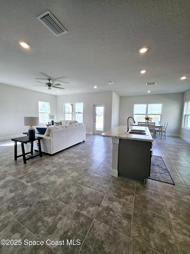 living room featuring sink, a textured ceiling, and ceiling fan