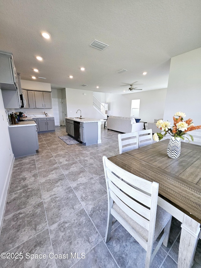 dining area featuring ceiling fan, sink, and a textured ceiling