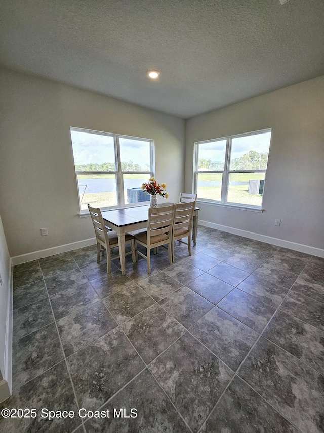 dining area with a textured ceiling and a water view