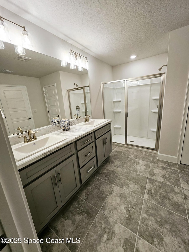 bathroom with vanity, a textured ceiling, and walk in shower