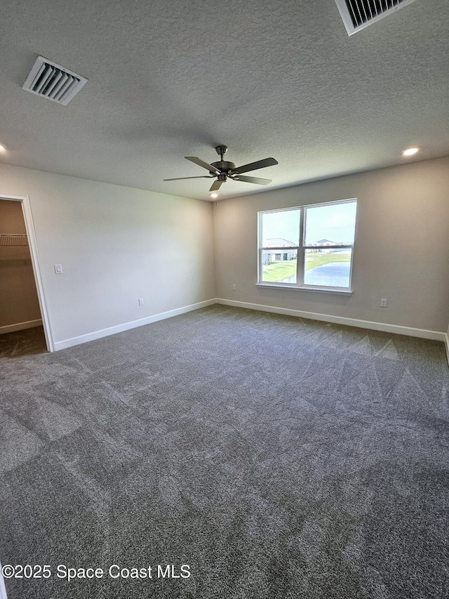 carpeted spare room with ceiling fan and a textured ceiling