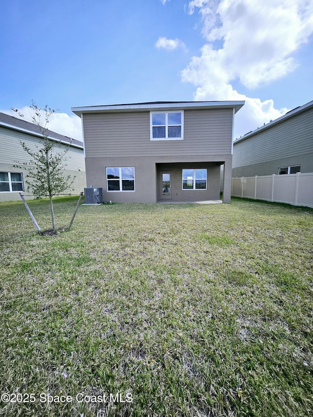 rear view of house with central AC and a lawn