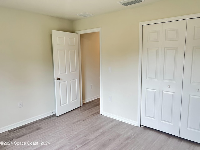 unfurnished bedroom with light wood-type flooring and a closet