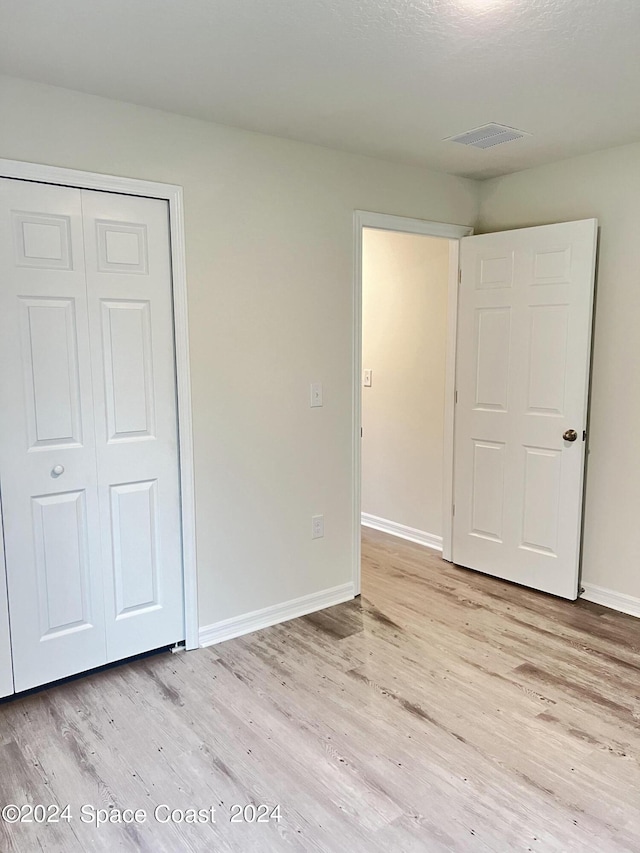 unfurnished bedroom featuring a closet and light hardwood / wood-style floors