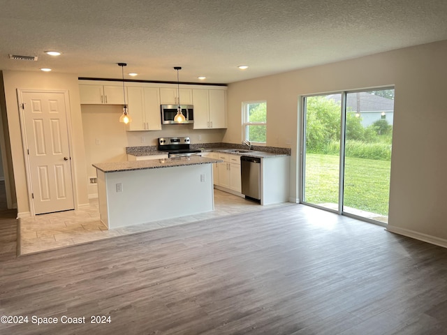 kitchen featuring a kitchen island, pendant lighting, light hardwood / wood-style flooring, and stainless steel appliances