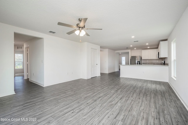 unfurnished living room featuring a textured ceiling, ceiling fan, and light hardwood / wood-style flooring