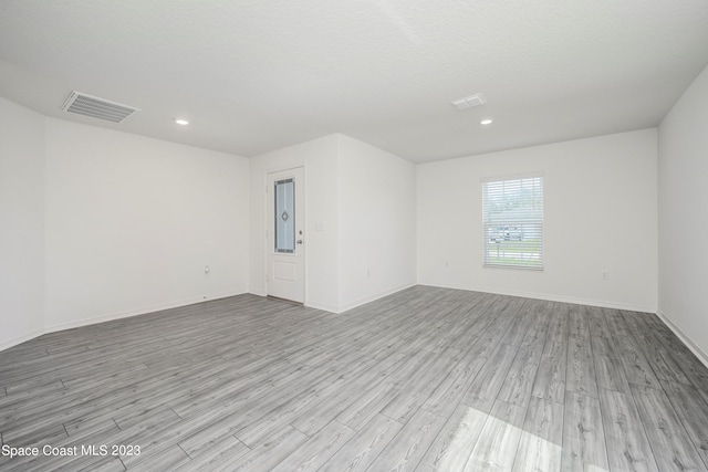 empty room featuring a textured ceiling and light hardwood / wood-style floors