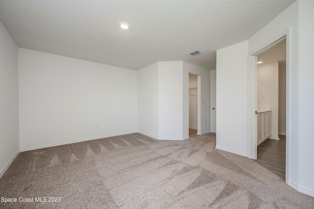 spare room featuring light carpet and a textured ceiling