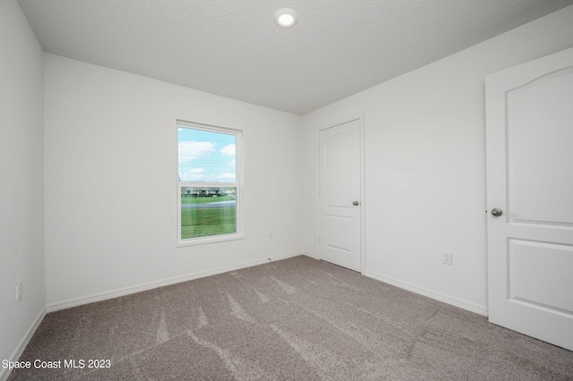 unfurnished room with a textured ceiling and carpet flooring