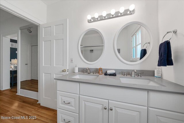 bathroom featuring hardwood / wood-style flooring and dual bowl vanity