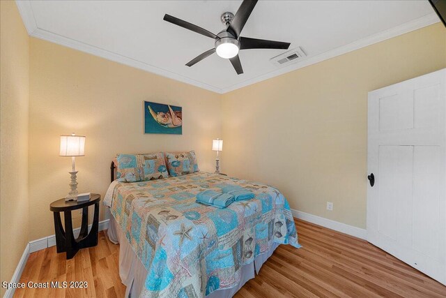 bedroom with ornamental molding, ceiling fan, and light wood-type flooring