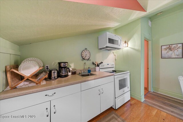 kitchen featuring white appliances, light hardwood / wood-style floors, sink, white cabinets, and a textured ceiling