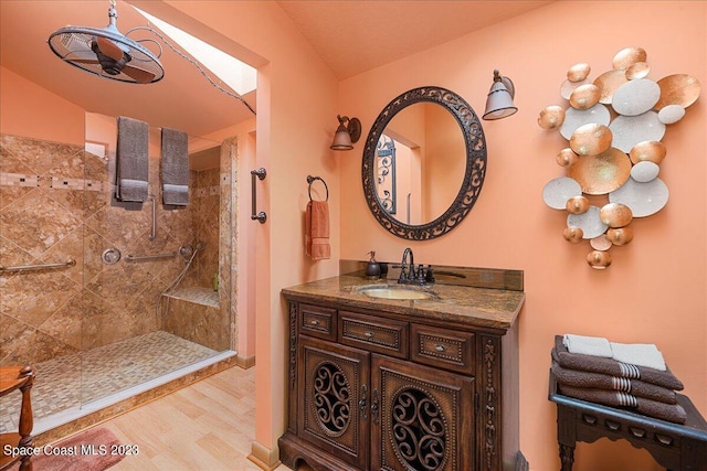 bathroom featuring hardwood / wood-style floors, vanity, tiled shower, and lofted ceiling