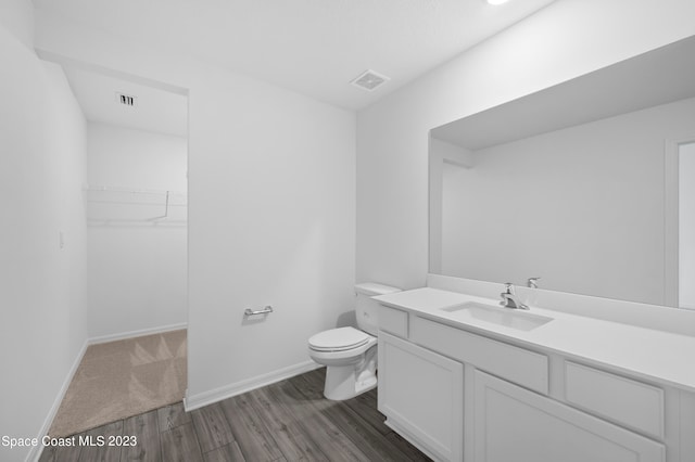 bathroom featuring oversized vanity, toilet, and wood-type flooring