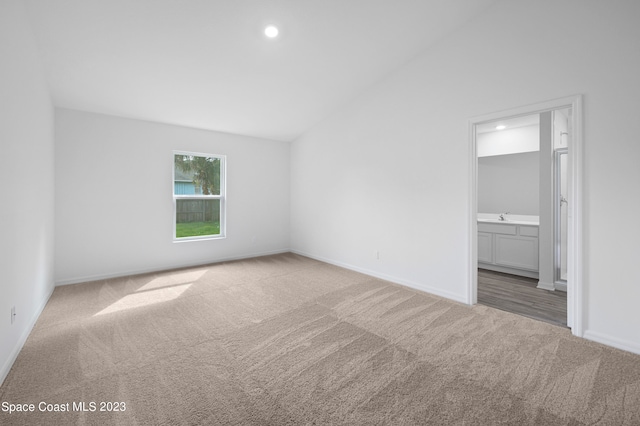 empty room with light colored carpet and vaulted ceiling