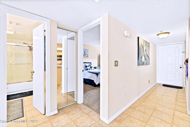 corridor with a textured ceiling and light tile floors