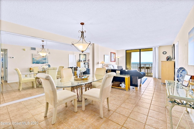 tiled dining space featuring a water view, a textured ceiling, and expansive windows