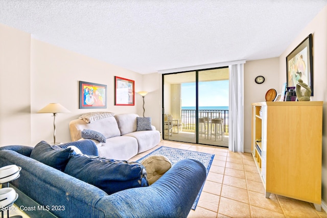 living room with light tile floors, a textured ceiling, a wall of windows, and a water view