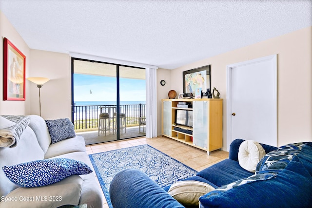 tiled living room featuring a water view, a textured ceiling, and a wall of windows