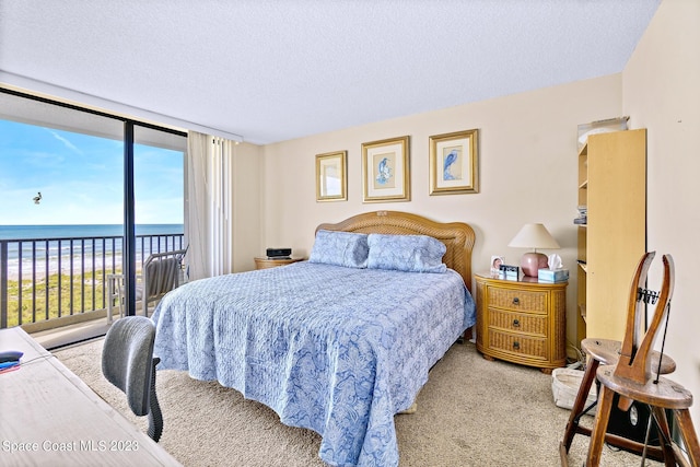 carpeted bedroom with a water view, a textured ceiling, and access to exterior