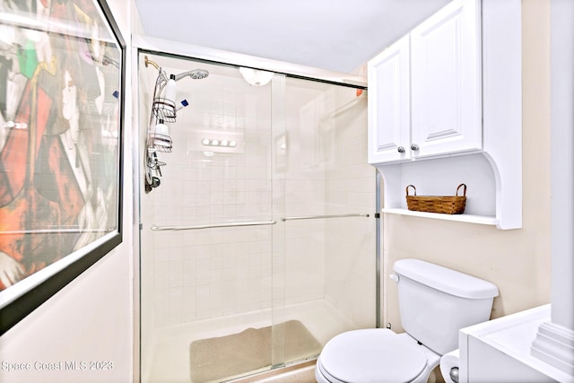 bathroom with a shower with door and toilet