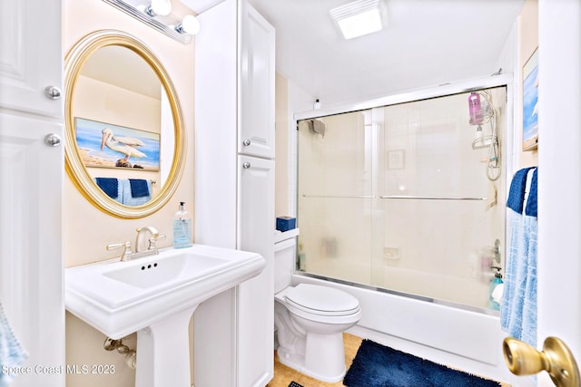 full bathroom featuring combined bath / shower with glass door, toilet, tile floors, and sink