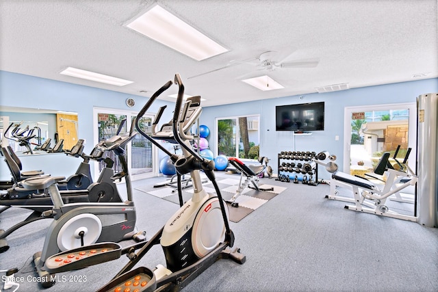 workout area featuring a textured ceiling, ceiling fan, and light colored carpet