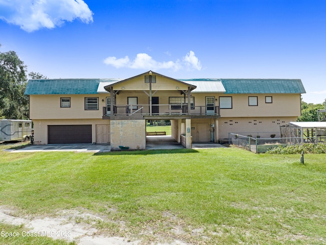 view of front facade with a balcony, a front yard, and a garage