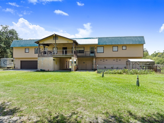 back of property featuring a balcony, a garage, and a yard