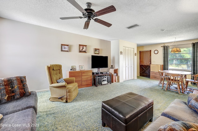 carpeted living room featuring ceiling fan and a textured ceiling