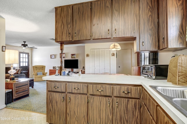 kitchen featuring kitchen peninsula, ceiling fan, sink, a textured ceiling, and light colored carpet