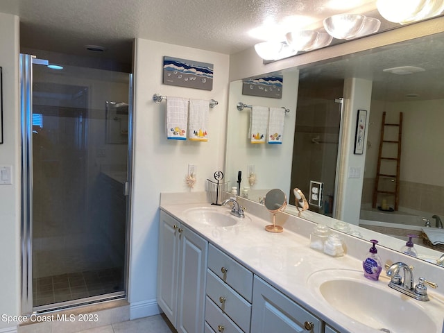 bathroom with tile floors, independent shower and bath, dual sinks, oversized vanity, and a textured ceiling