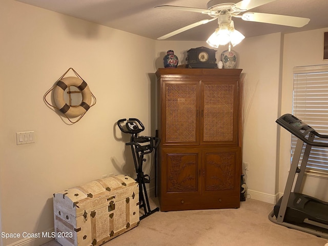 exercise area featuring light carpet and ceiling fan