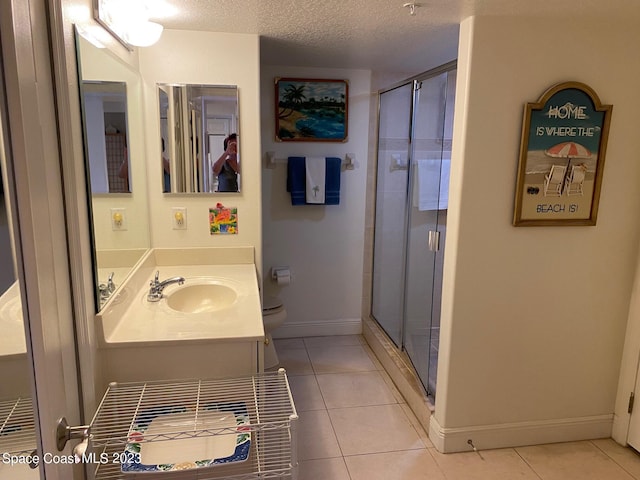 bathroom with a textured ceiling, a shower with door, vanity with extensive cabinet space, and tile flooring