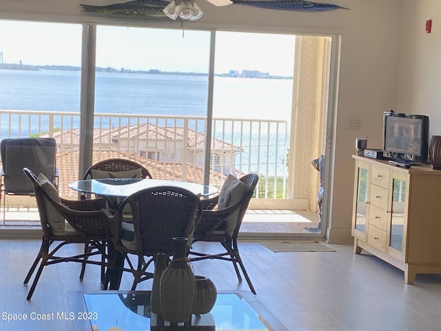 dining room with light hardwood / wood-style flooring, ceiling fan, and a water view