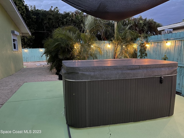 patio terrace at dusk featuring a hot tub