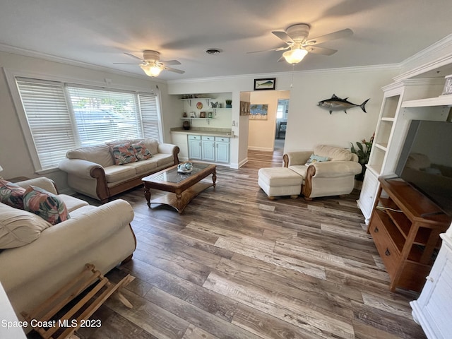 living room featuring dark wood-type flooring, ornamental molding, and ceiling fan