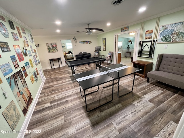 playroom with crown molding, ceiling fan, and dark wood-type flooring