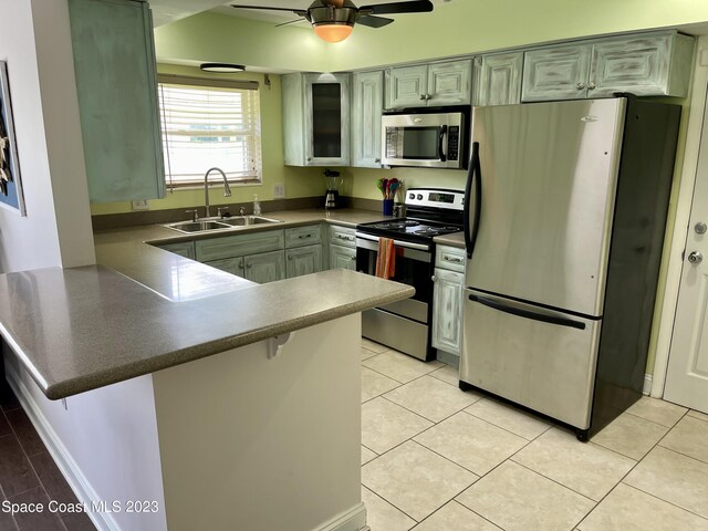 kitchen with kitchen peninsula, ceiling fan, appliances with stainless steel finishes, sink, and light tile floors