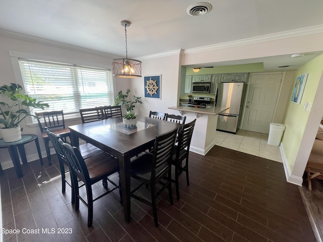 dining space with dark tile flooring, ornamental molding, and an inviting chandelier