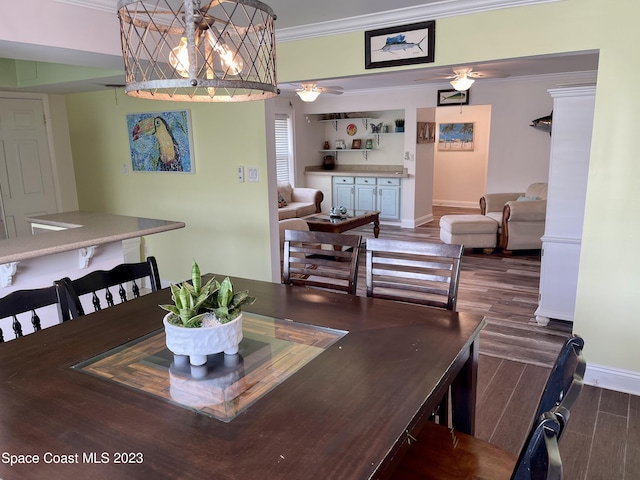 dining area featuring dark hardwood / wood-style floors, ornamental molding, and ceiling fan with notable chandelier