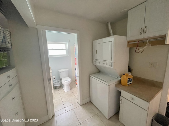 washroom featuring light tile floors and stacked washer and dryer