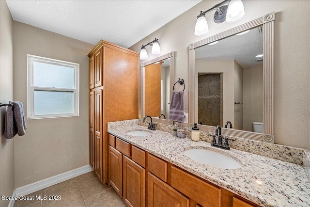 bathroom with toilet, tile floors, and double sink vanity