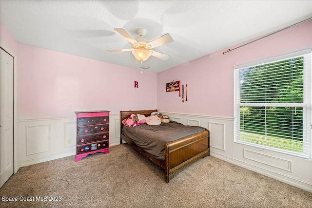 carpeted bedroom featuring a textured ceiling, ceiling fan, and multiple windows