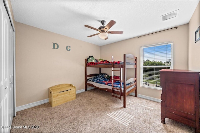 carpeted bedroom featuring a closet, ceiling fan, and a textured ceiling