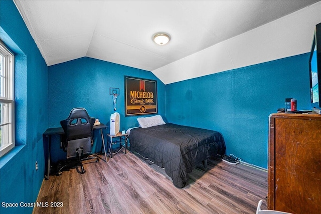 bedroom with dark hardwood / wood-style floors, vaulted ceiling, and multiple windows